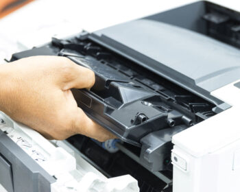Showing a person's hand removing a printer cartage with a new one.